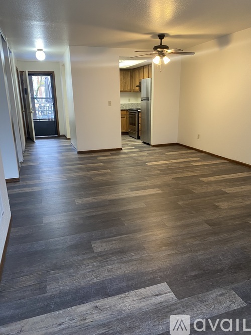 A spacious room with wooden flooring and a ceiling fan.