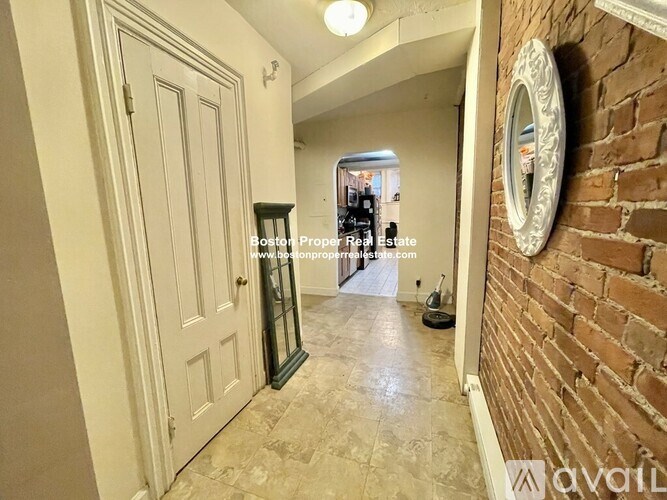 A hallway with a brick wall and a mirror on the wall.