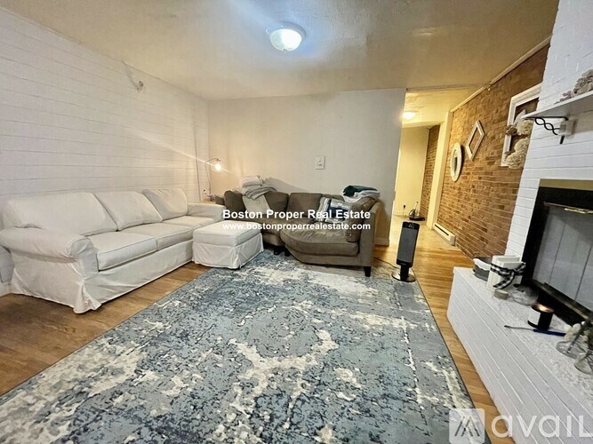 A living room with a white couch and a blue rug.