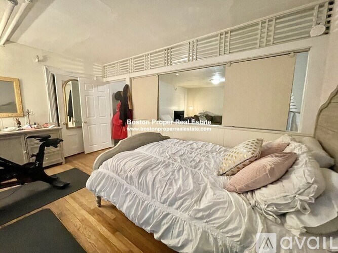 A bedroom with a large bed and a mirror on the wall.