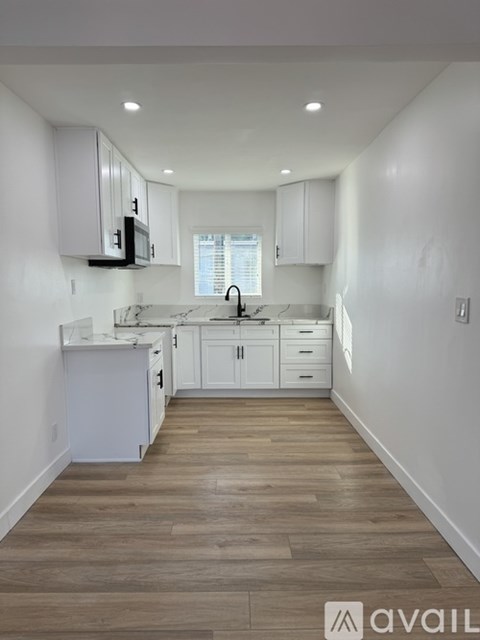 A kitchen with white cabinets and a wooden floor.