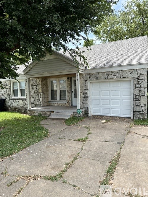A house with a white garage door and a stone wall.