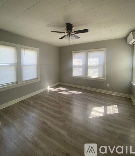 A room with a ceiling fan and wood flooring.