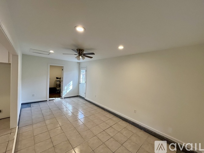 A spacious room with a ceiling fan and tiled flooring.
