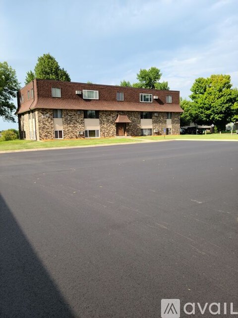 A stone building with a brown roof and a parking lot in front.