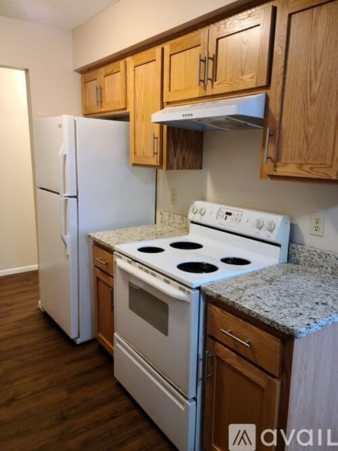 A kitchen with a white stove top oven and a white refrigerator.