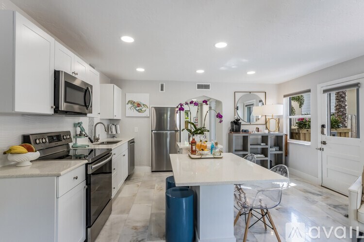 A kitchen with white cabinets and a blue trash can.