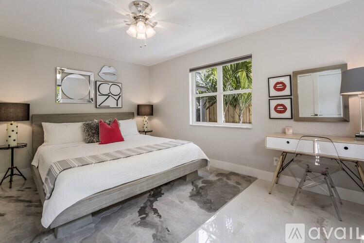 A bedroom with a large bed, a desk, and a window with a view of greenery outside.