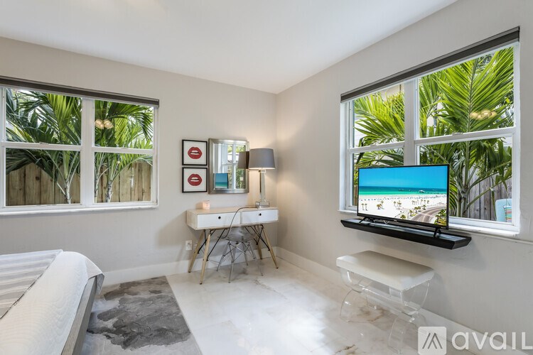 A room with a bed, desk, and a television displaying a beach scene.