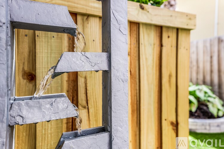 Water flows from a metal pipe into a wooden container.
