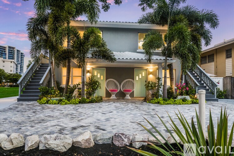 A house with a front yard and palm trees.