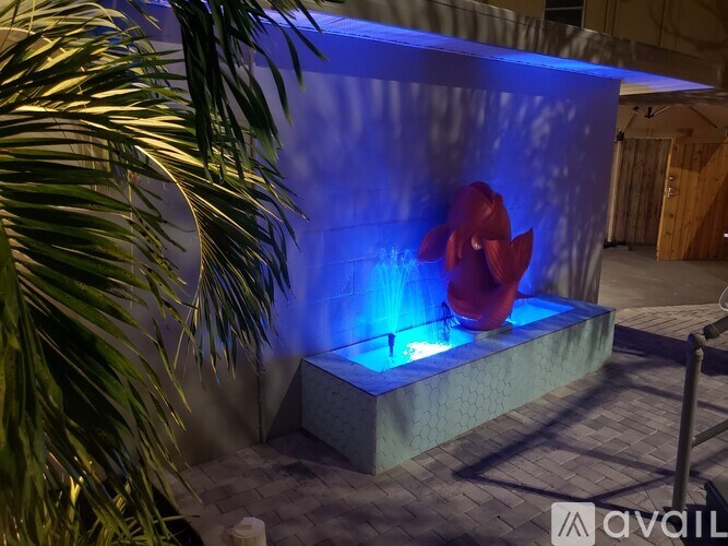 A red flower is illuminated by blue light in a dark room.