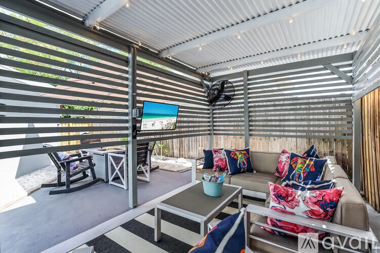 A modern outdoor living space with a sofa, chairs, and a television.
