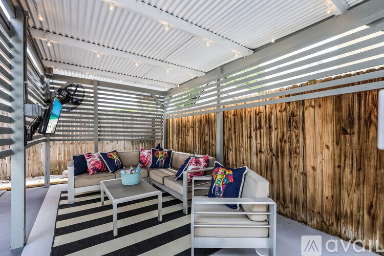 A modern outdoor seating area with a white sofa and a glass coffee table.