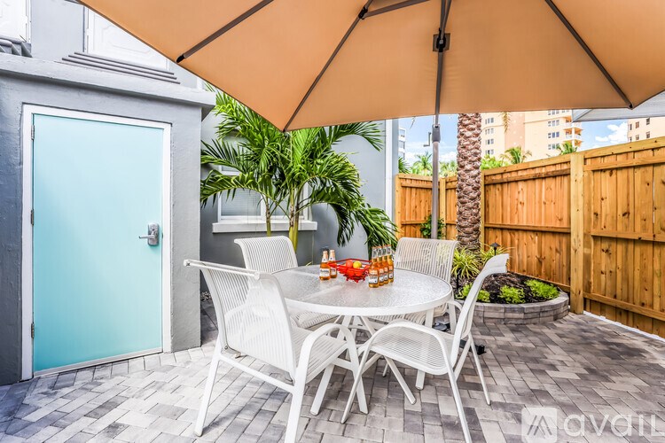 A patio with a table and chairs under an umbrella.