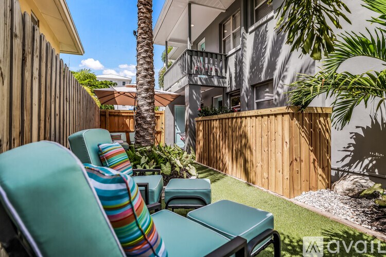 A patio with a wooden fence and a palm tree.