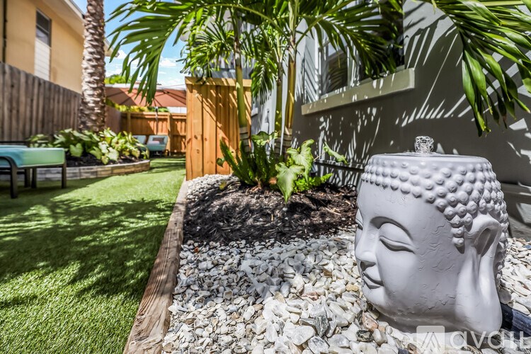 A white Buddha statue is in a garden with a gravel bed.
