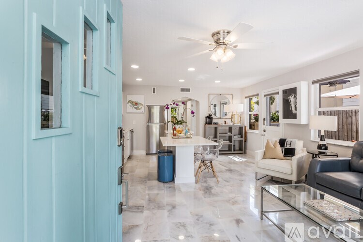 A modern living room with a glass table and a blue door.