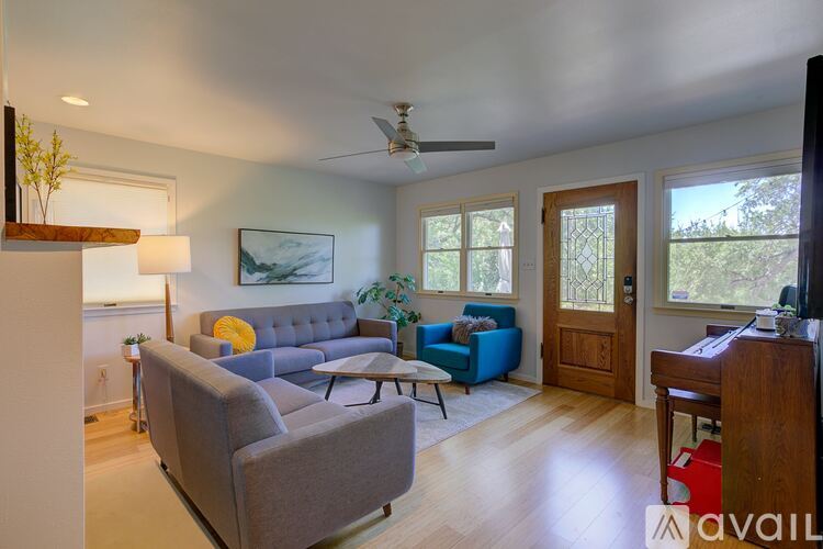 A living room with a grey couch, a blue couch, a wooden table, and a ceiling fan.