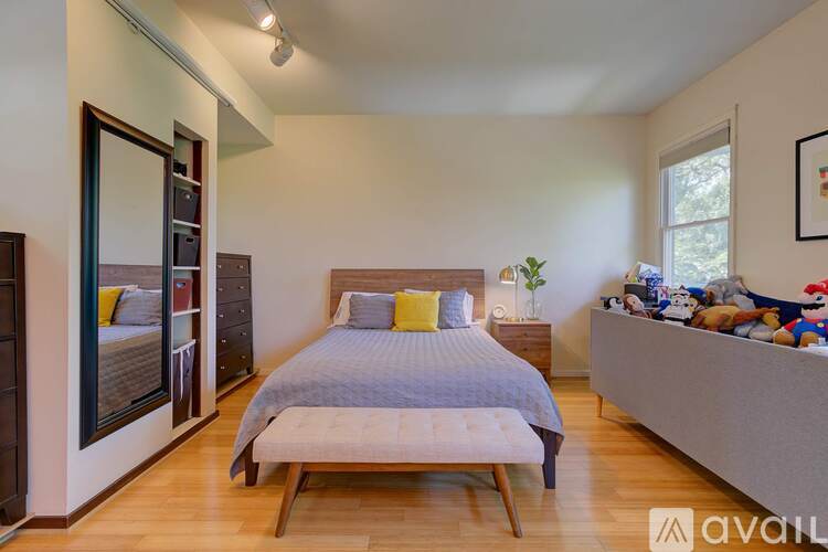A bedroom with a bed, a nightstand, and a window.