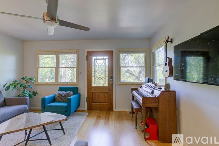 A living room with a blue chair and a wooden piano.