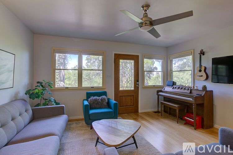 A living room with a grey sofa, a blue chair, a wooden coffee table, and a ceiling fan.