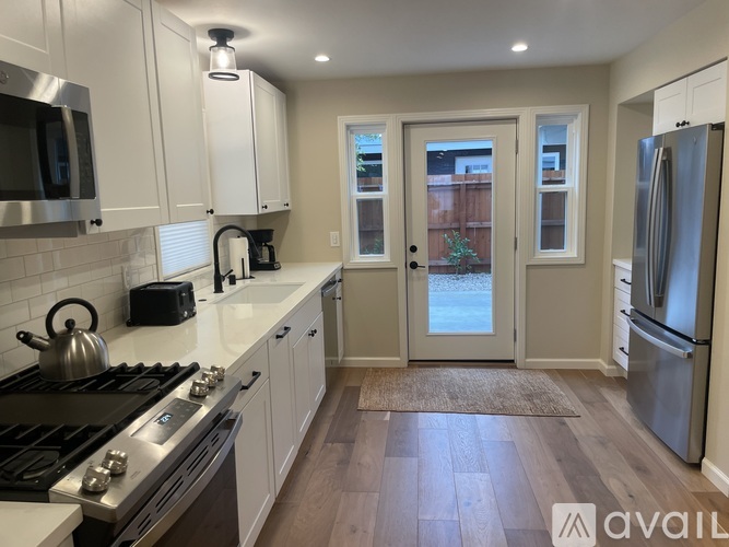A kitchen with white cabinets and a stainless steel refrigerator.
