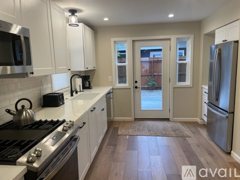 A kitchen with white cabinets and a stainless steel refrigerator.