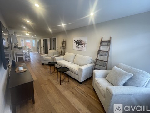 A living room with white furniture and wooden floors.