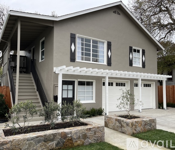 A house with a grey facade and a white pergola.