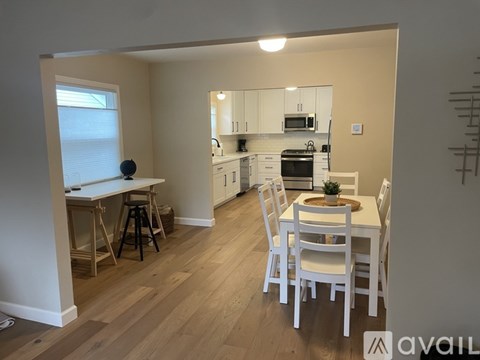A kitchen with white chairs and a dining table.
