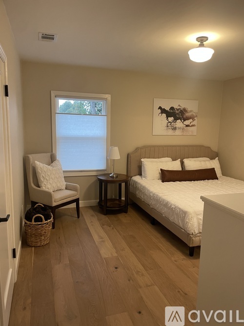 A bedroom with a bed, chair, and window.