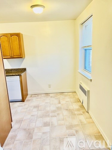 A kitchen area with wooden cabinets and a tiled floor.