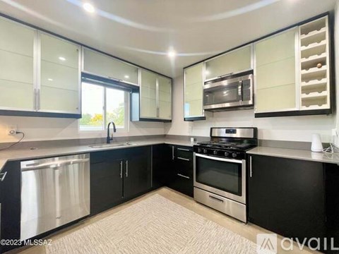 A modern kitchen with black cabinets and stainless steel appliances.