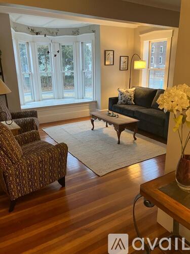 A living room with a black couch, a patterned chair, and a coffee table.