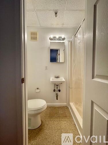 A bathroom with a toilet, sink, and mirror.