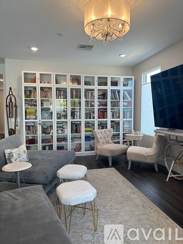 A living room with a grey sofa, a white chair, and a chandelier.