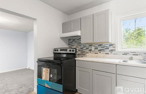 A kitchen with a black stove and a window overlooking a green area.
