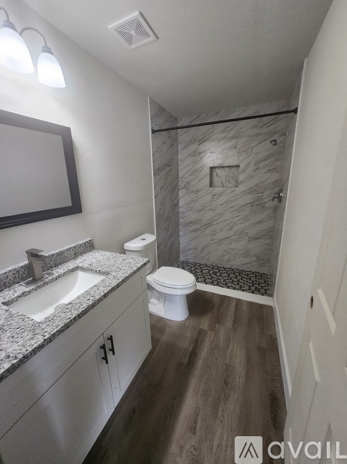 A bathroom with a marble shower and a white toilet.