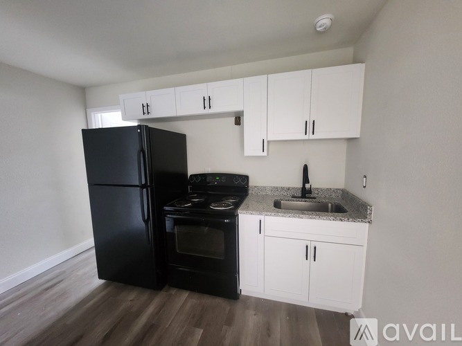 A black refrigerator and oven in a kitchen with white cabinets.