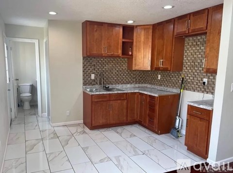 A kitchen with brown cabinets and a marble countertop.