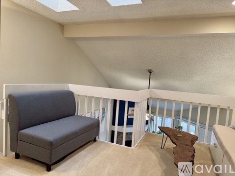 A living room with a grey sofa and a skylight.