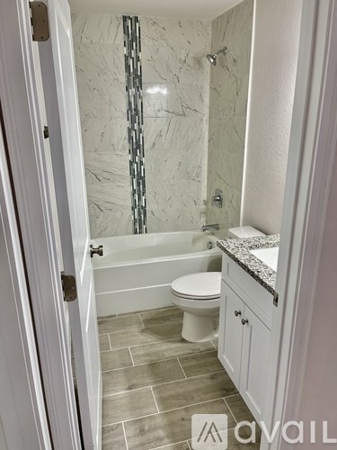A white bathroom with a marble shower and a toilet.