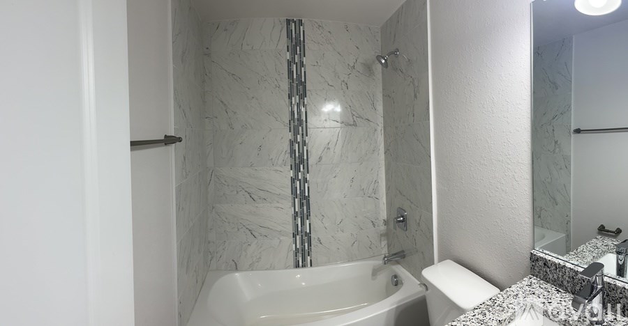 A white bathroom with a marble wall and a white bathtub.