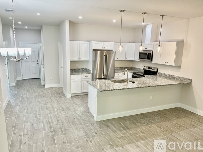 A spacious kitchen with a central island, stainless steel appliances, and pendant lights.