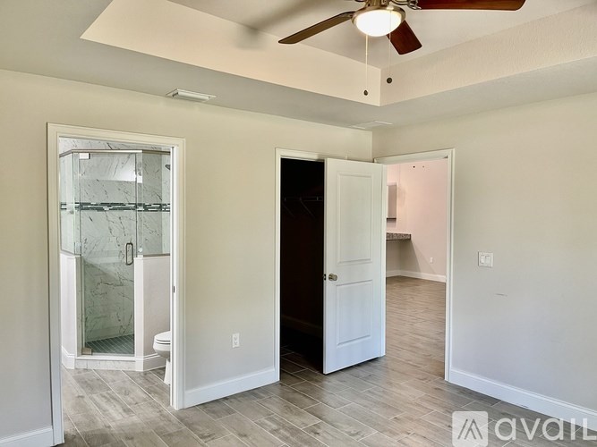 A room with a ceiling fan and a glass door shower.