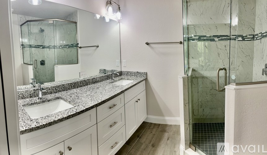 A bathroom with a marble countertop and a walk-in shower.
