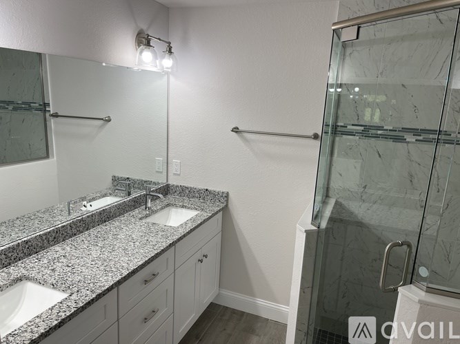 A bathroom with a marble countertop and a walk-in shower.
