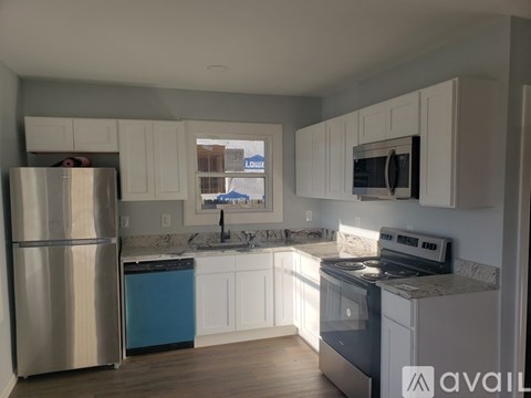 A kitchen with a stainless steel refrigerator and white cabinets.