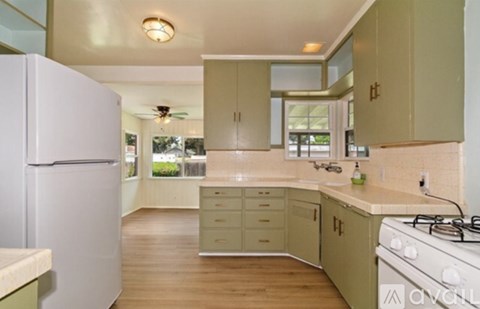A kitchen with a white refrigerator and wooden floors.
